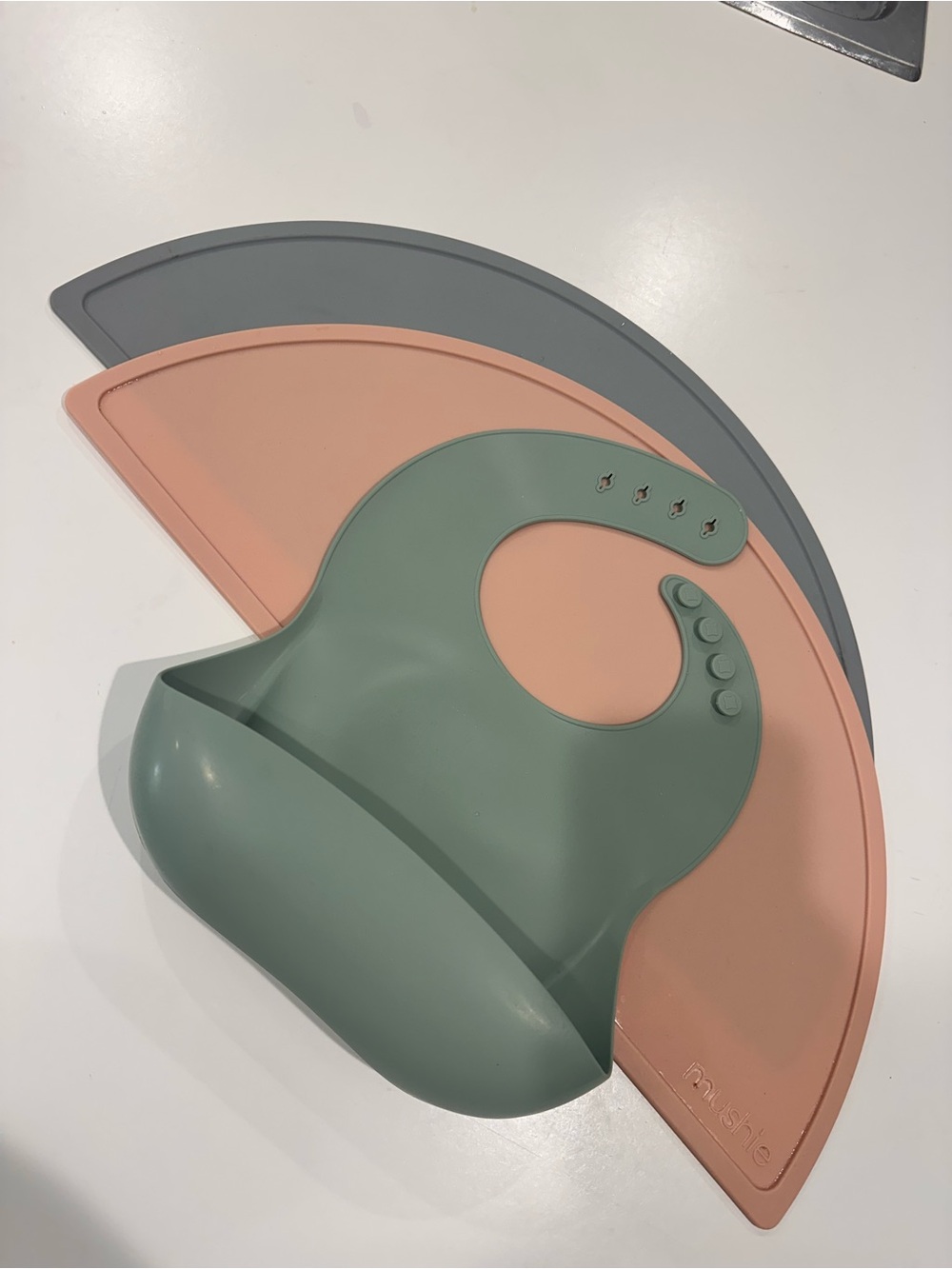 Mushie Sage Green Bib and Mushie Silicone Placemat in Stone and Blush